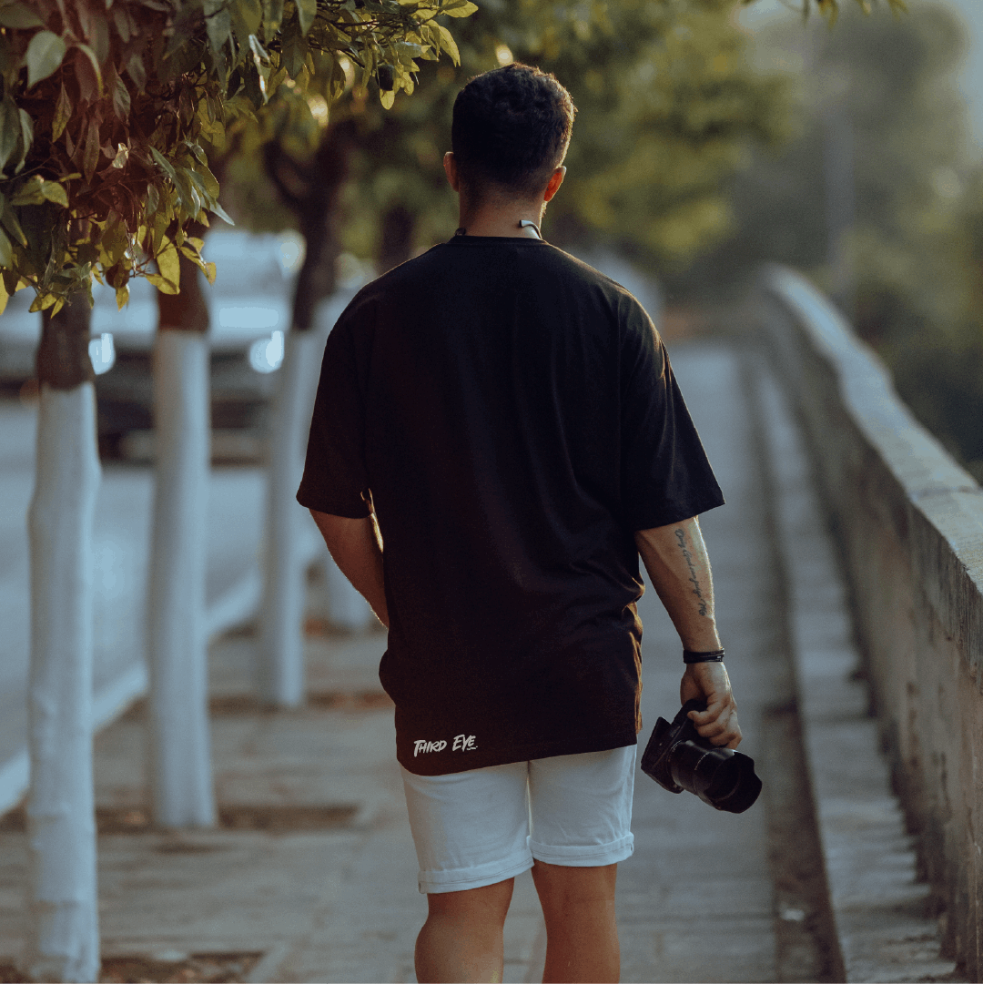 A man wearing a black Third Eye Clothing tee walking away. The photo is taken from behind so you can clearly see the Third Eye Clothing logo on the back of the T-Shirt
